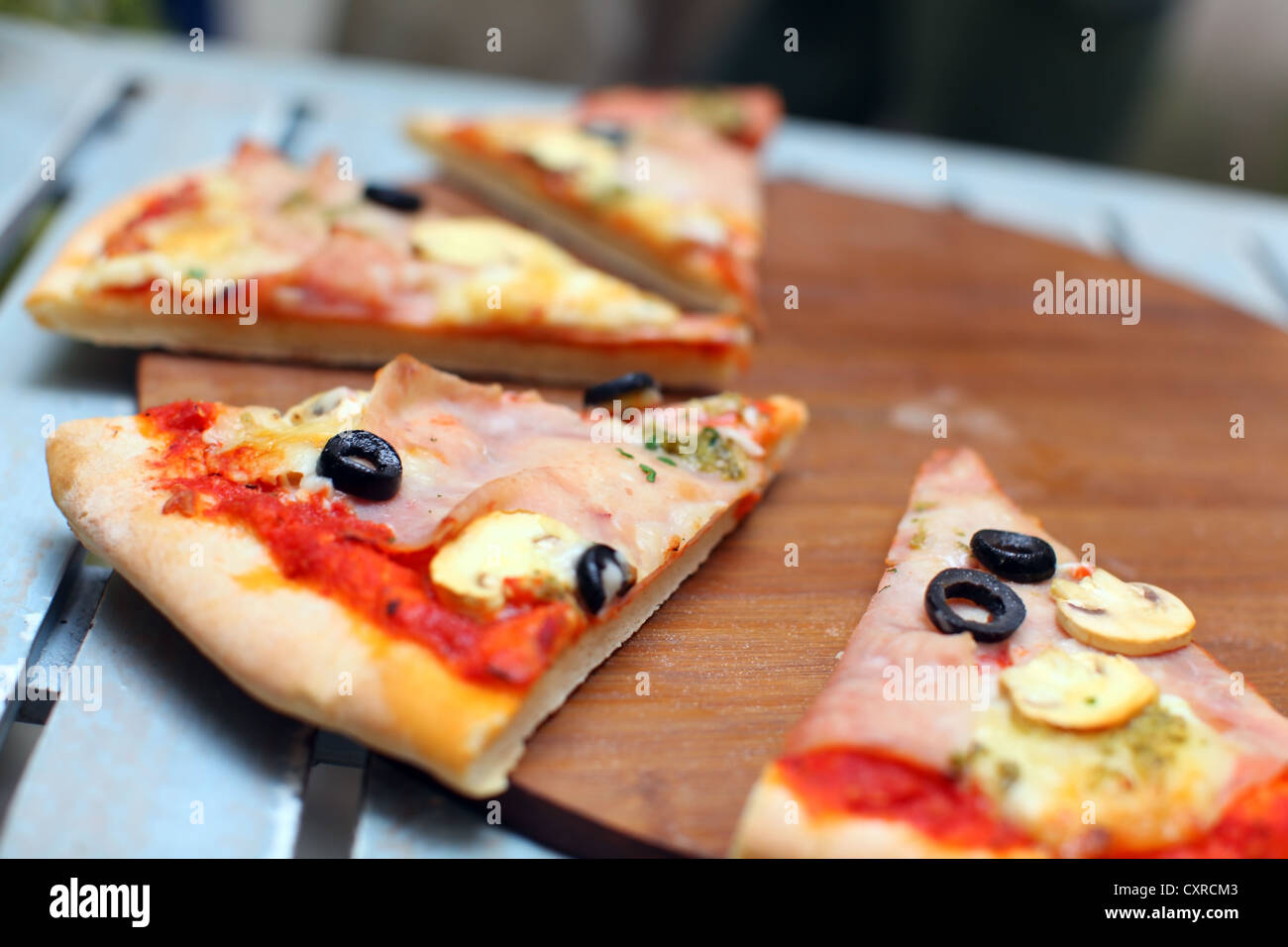 Pizza mit Schinken und Oliven auf einem Holzbrett geschnitten Stockfoto