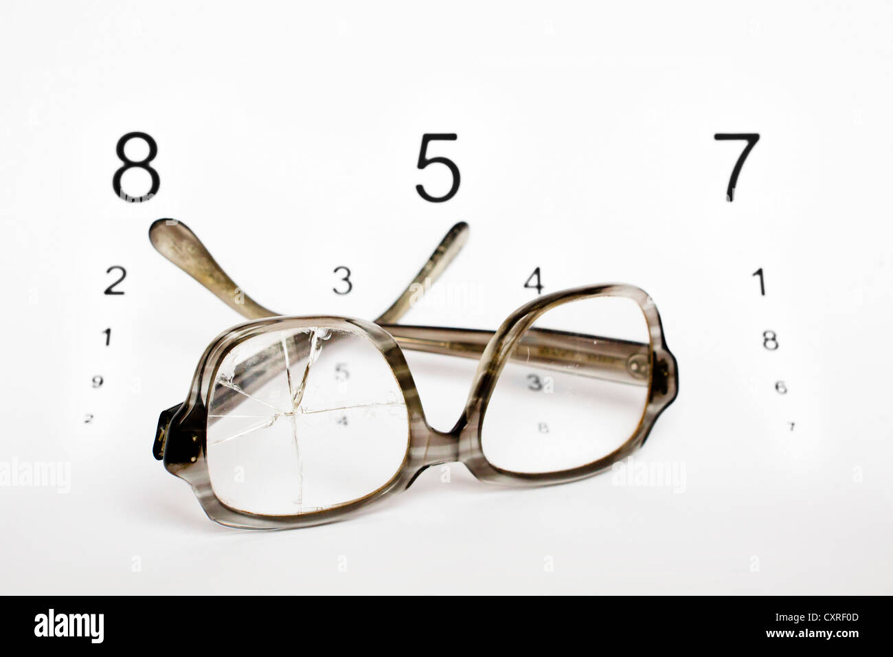 Alte kaputte Brille mit einem Auge Testchart Stockfoto
