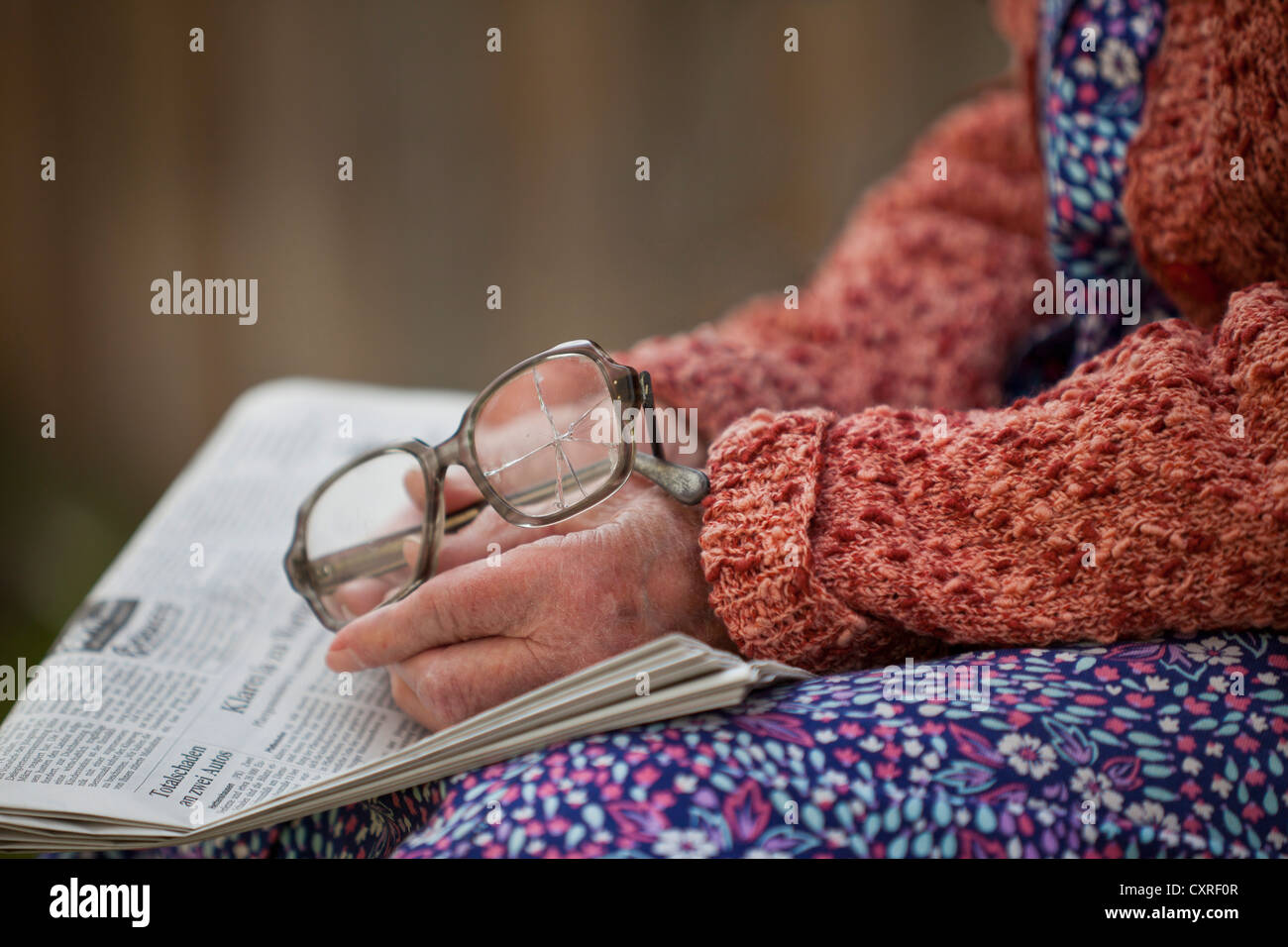 Hände einer alten Frau hält alte zerbrochene Gläser auf einer Zeitung Stockfoto