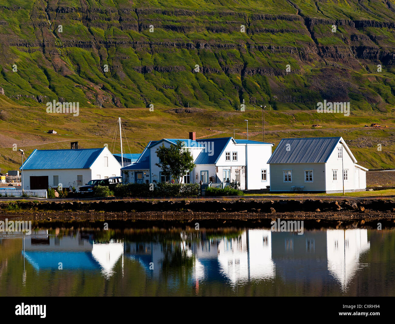 Reflexion auf See, blaue Dach-Häuser in Seydisfjordur, Osten, Island Stockfoto