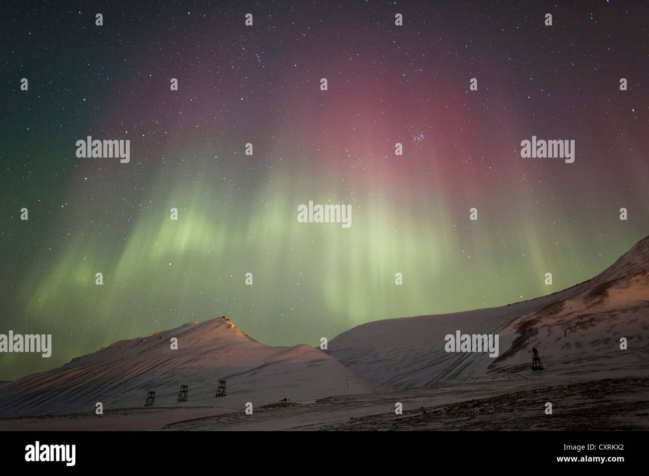 Grünes und rotes Polarlicht, Nordlicht, Aurora Borealis über eine verschneite Landschaft, Landschaft mit beleuchteten Stockfoto
