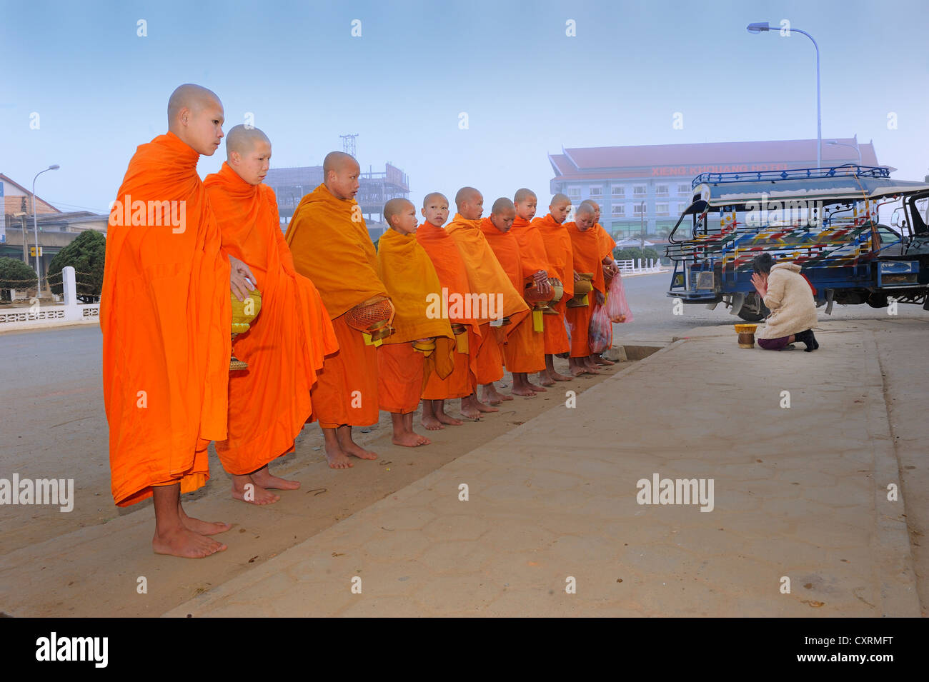 Buddhistische Bettelmönche in den frühen Morgenstunden, warten auf Almosen in der Hauptstraße von Phonsavan, Laos, Süd-Ost Asien Asien Stockfoto