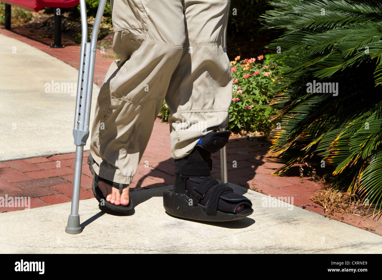 Der Mensch nutzt Krücken zusammen mit einer Fuß- und Sprunggelenk Orthese,  um ihm nach einem Unfallschaden laufen zu helfen Stockfotografie - Alamy