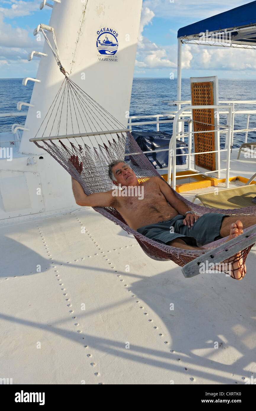 Älterer Mann, touristische liegen in der Hängematte auf der Okeanoss Aggressor, Cocos Island, Costa Rica, Mittelamerika Stockfoto