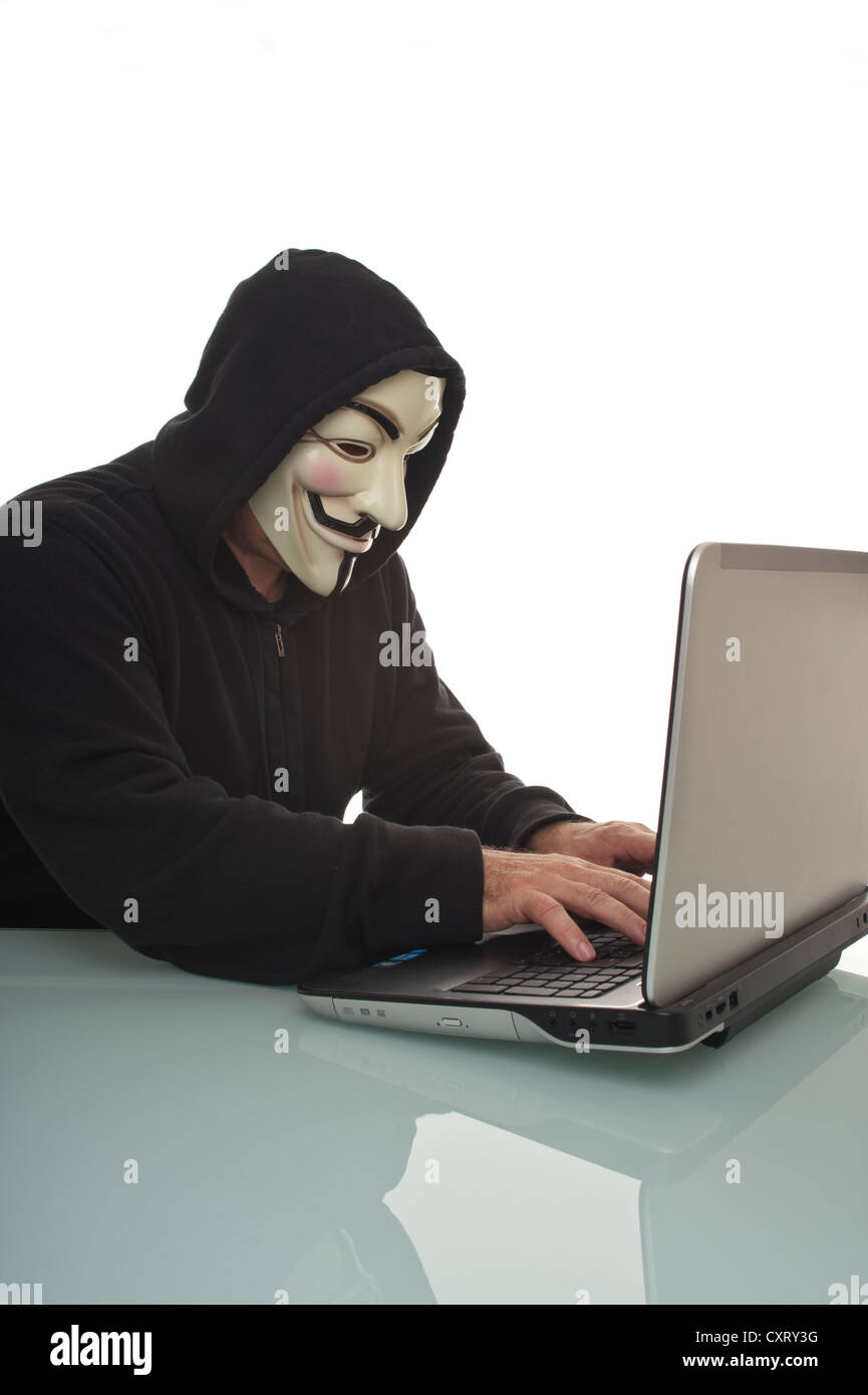 Mann trägt einen "Anonymous", Guy Fawkes oder "V for Vendetta" Maske, arbeitet auf einem Laptopcomputer Stockfoto