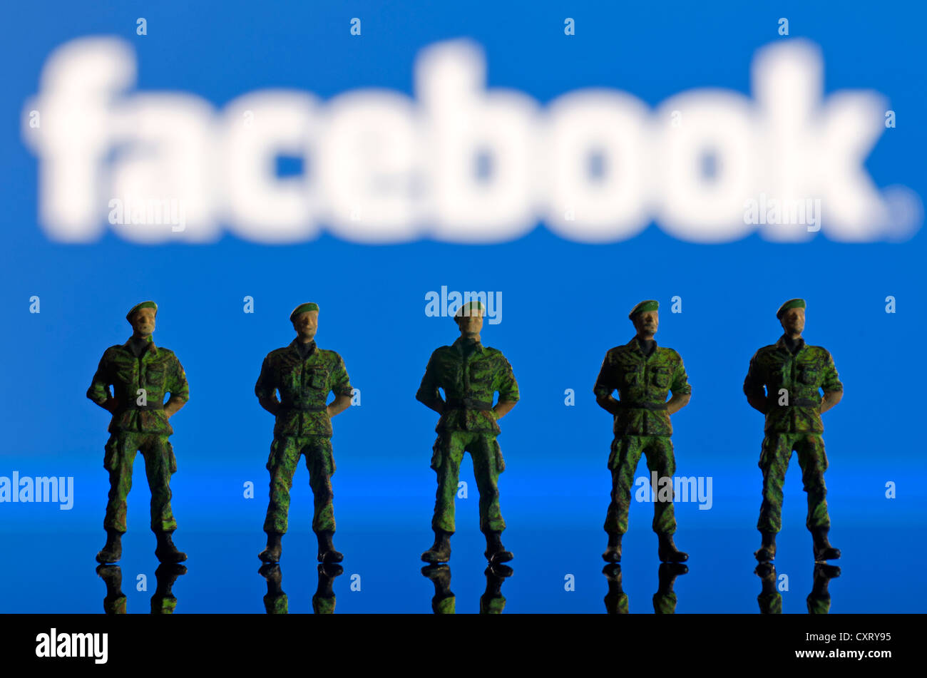 Eine Reihe von Soldaten, Miniaturfiguren, steht man vor einem unscharfen Facebook-Logo, symbolisches Bild Stockfoto