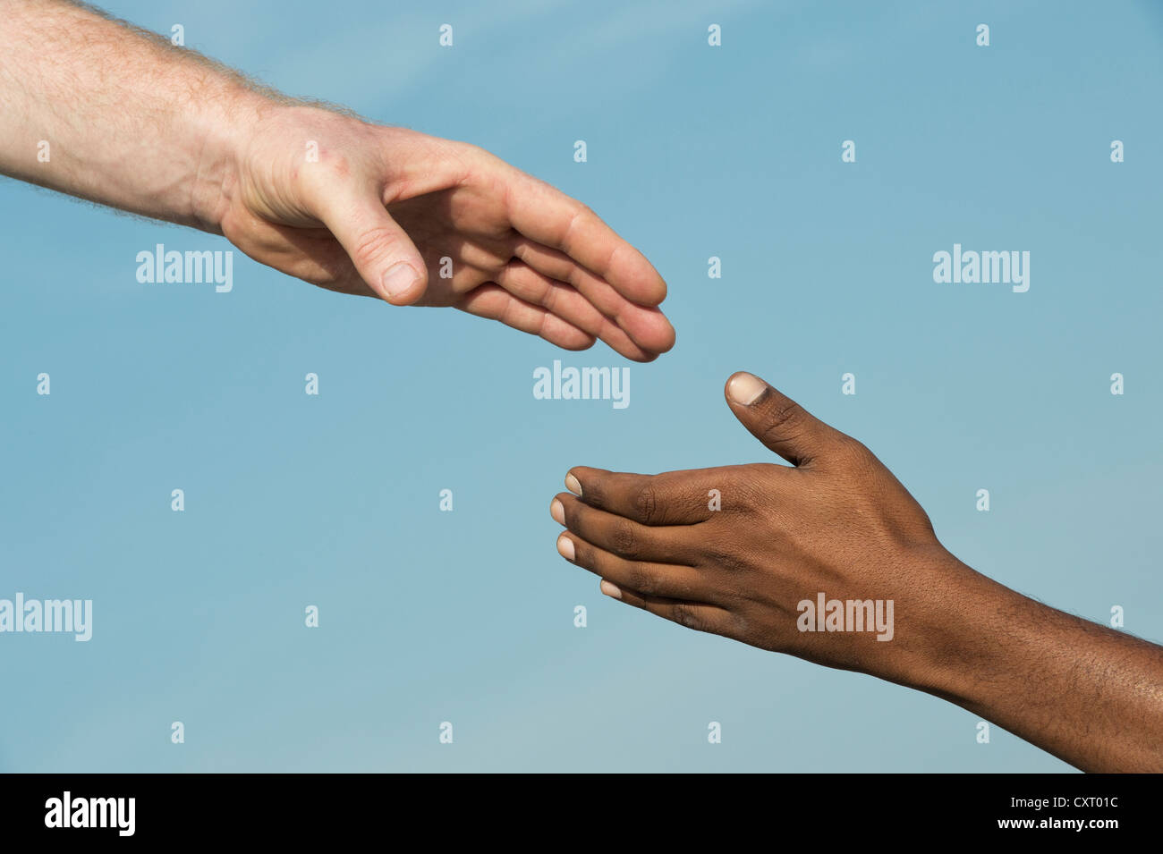 Westliche und östliche Hand schütteln vor blauem Himmel Stockfoto