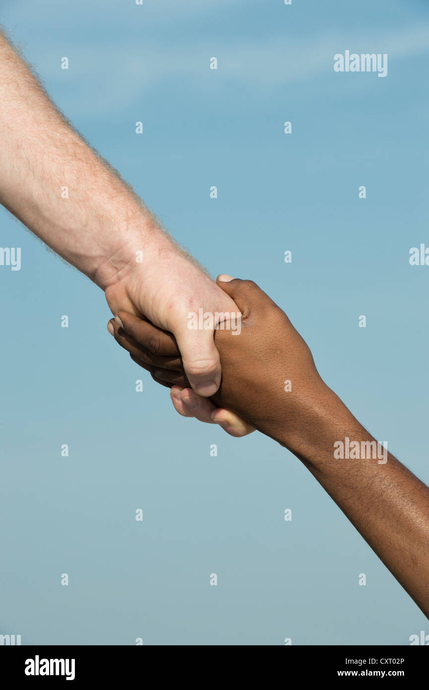 Westliche und östliche Hand schütteln vor blauem Himmel Stockfoto