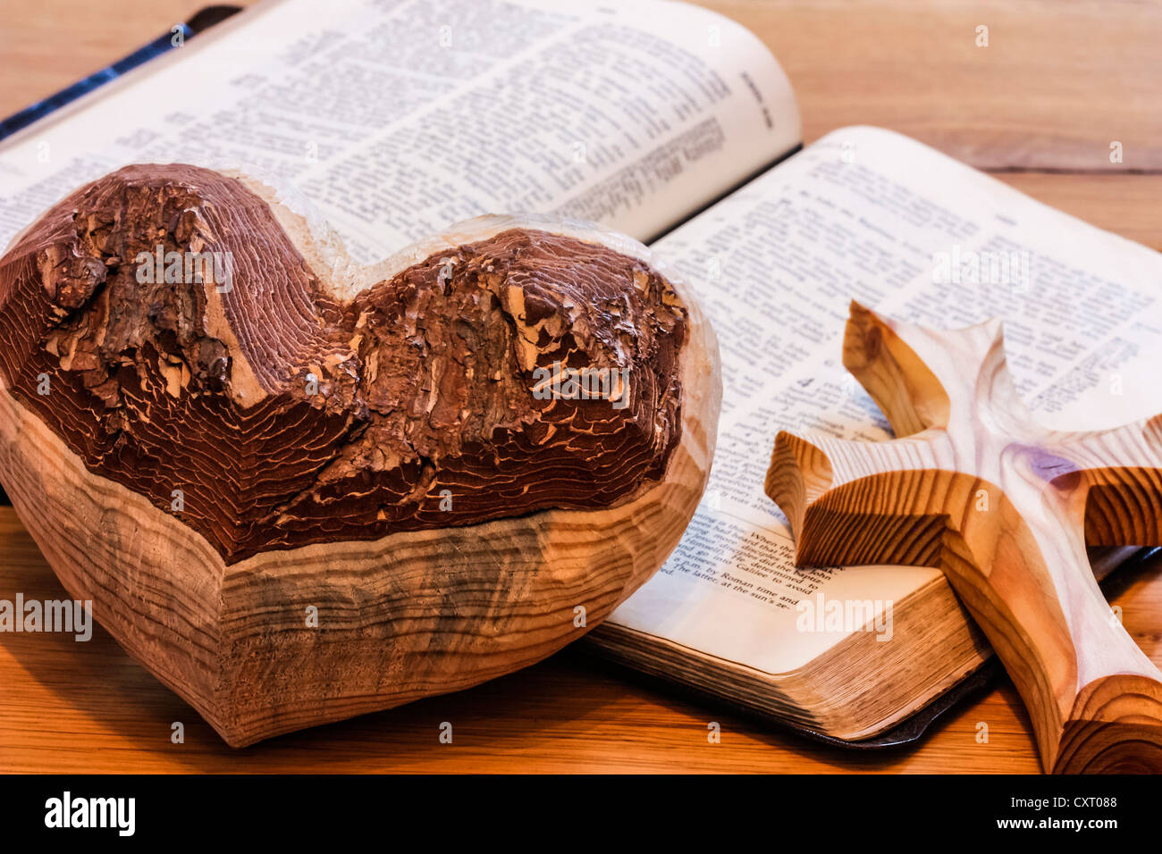 Herz aus Holz und einem hölzernen Kreuz liegen auf eine Bibel Stockfoto