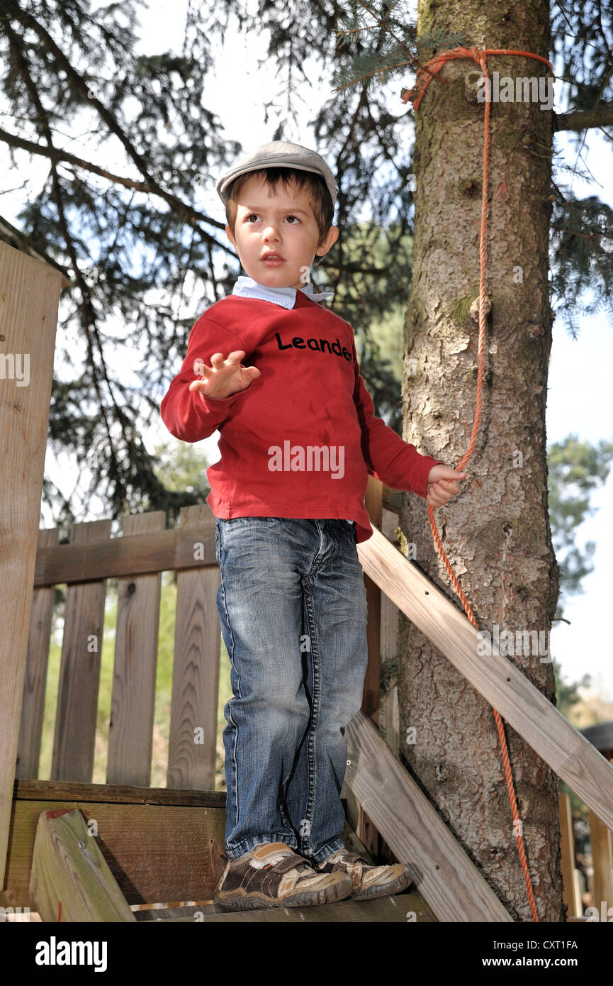Junge, 4, eine flache Kappe trägt und Seifenblasen vor einem Baum-Haus Stockfoto