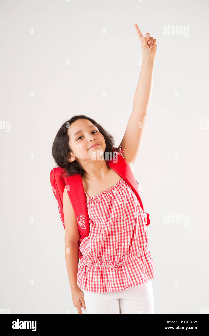 Mädchen mit Schulranzen nach oben zeigend Stockfoto