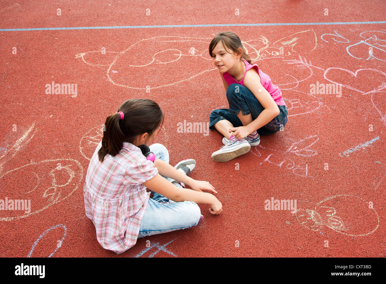 Zwei Mädchen sitzen gelangweilt auf dem Schulhof Stockfoto