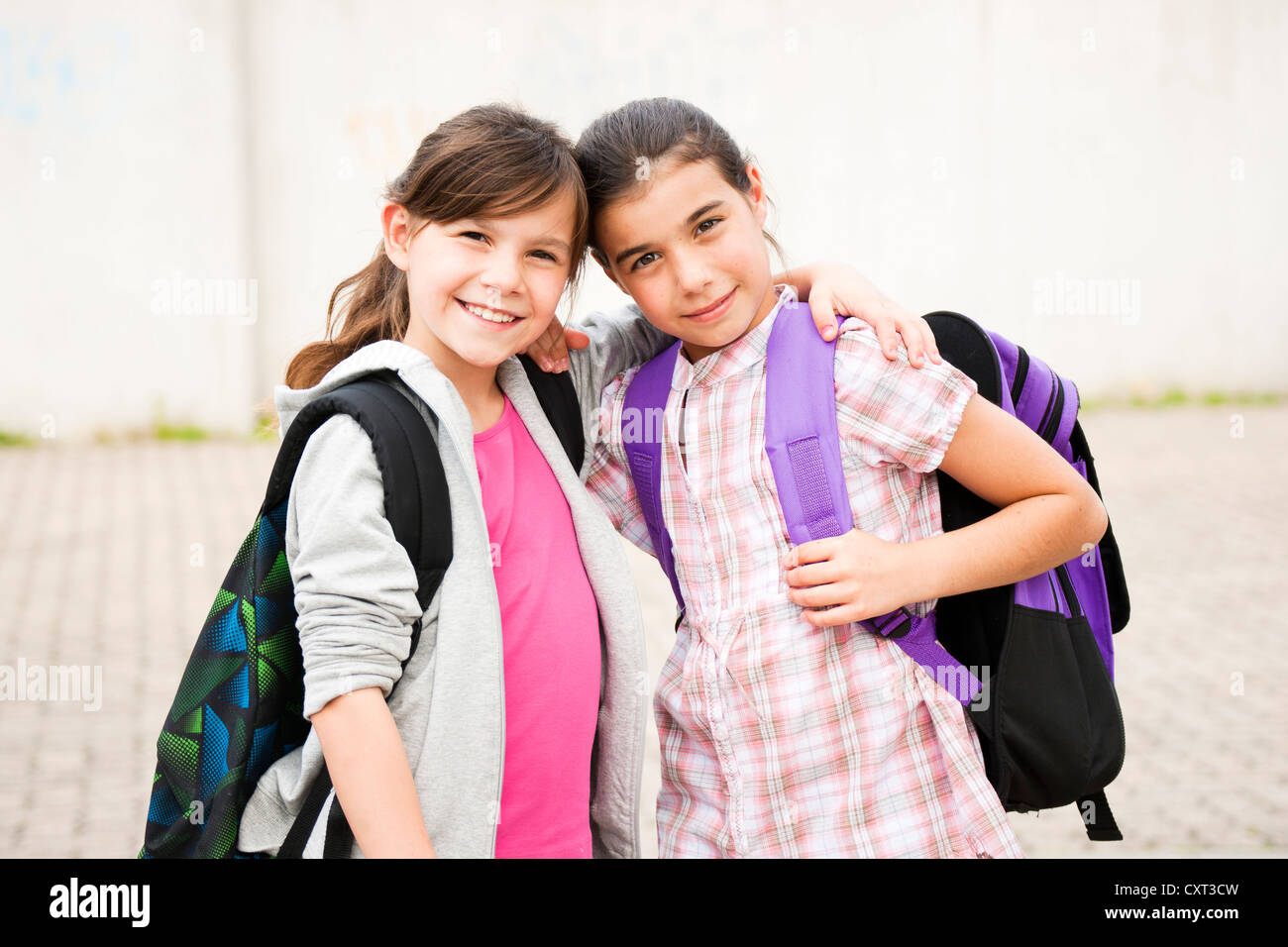 Zwei Mädchen stehen Arm in Arm auf dem Weg zur Schule Stockfoto