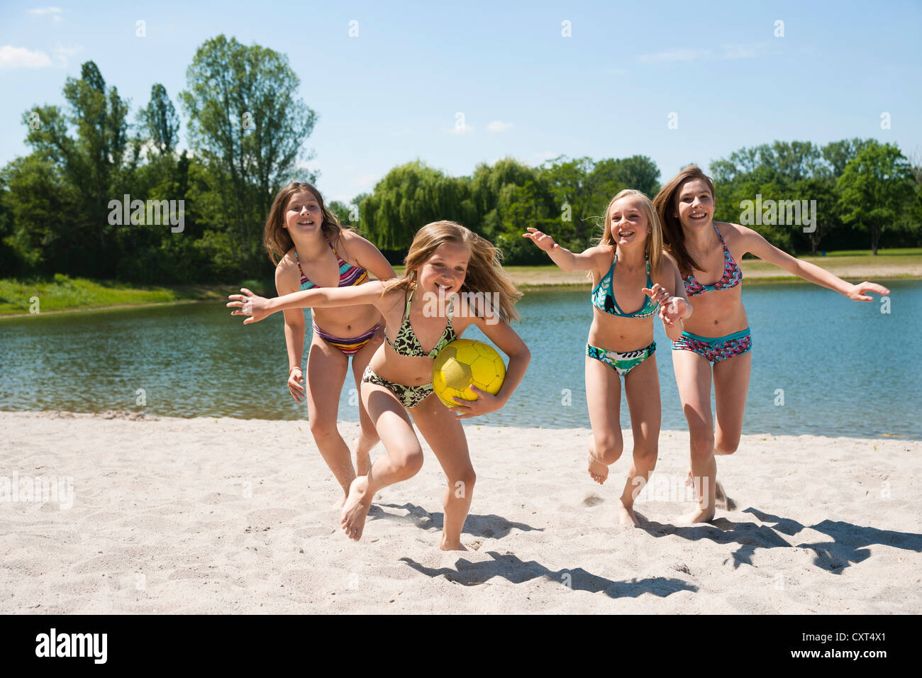 Gruppe von Mädchen spielen mit einem Ball am Strand eines Sees Stockfoto