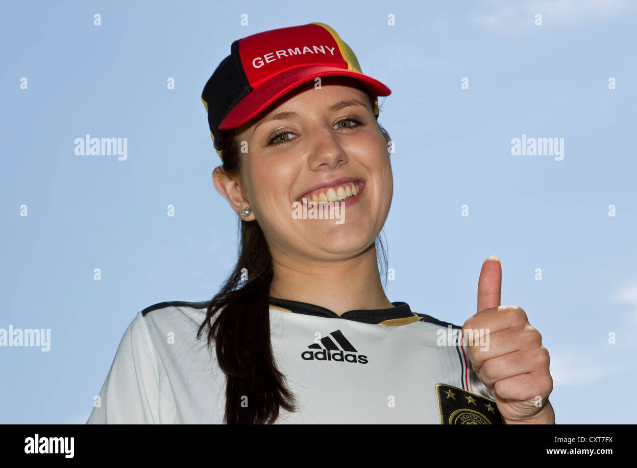 Junge Frau, Fußball-Fan trägt eine Deutschland-Kappe und Jersey, Porträt, ein Daumen-hoch-Geste Stockfoto