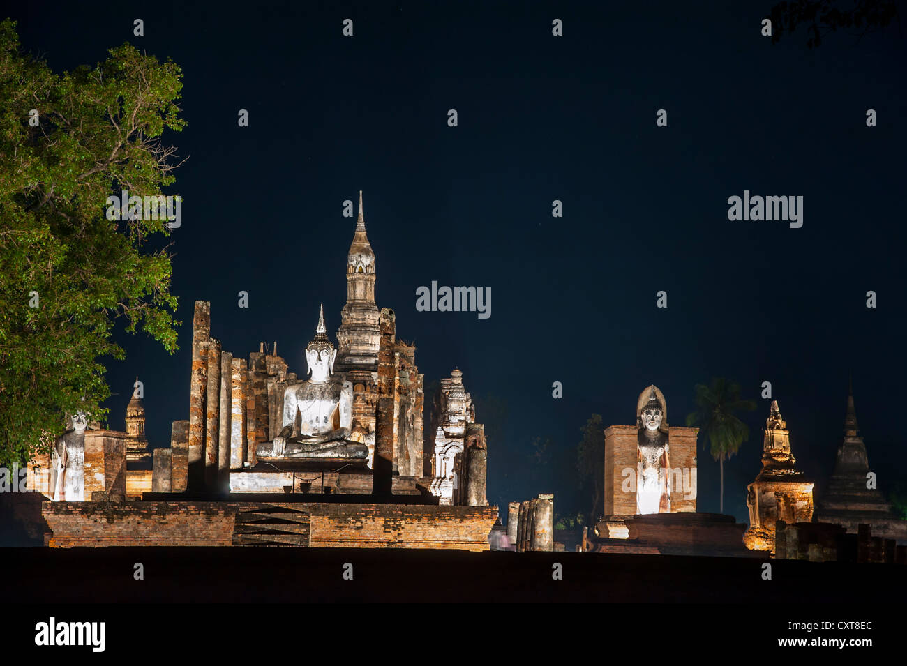 Sitzende und stehende Buddha-Statuen im Tempel Wat Mahathat, nachts, Sukhothai Historical Park, UNESCO-Weltkulturerbe Stockfoto
