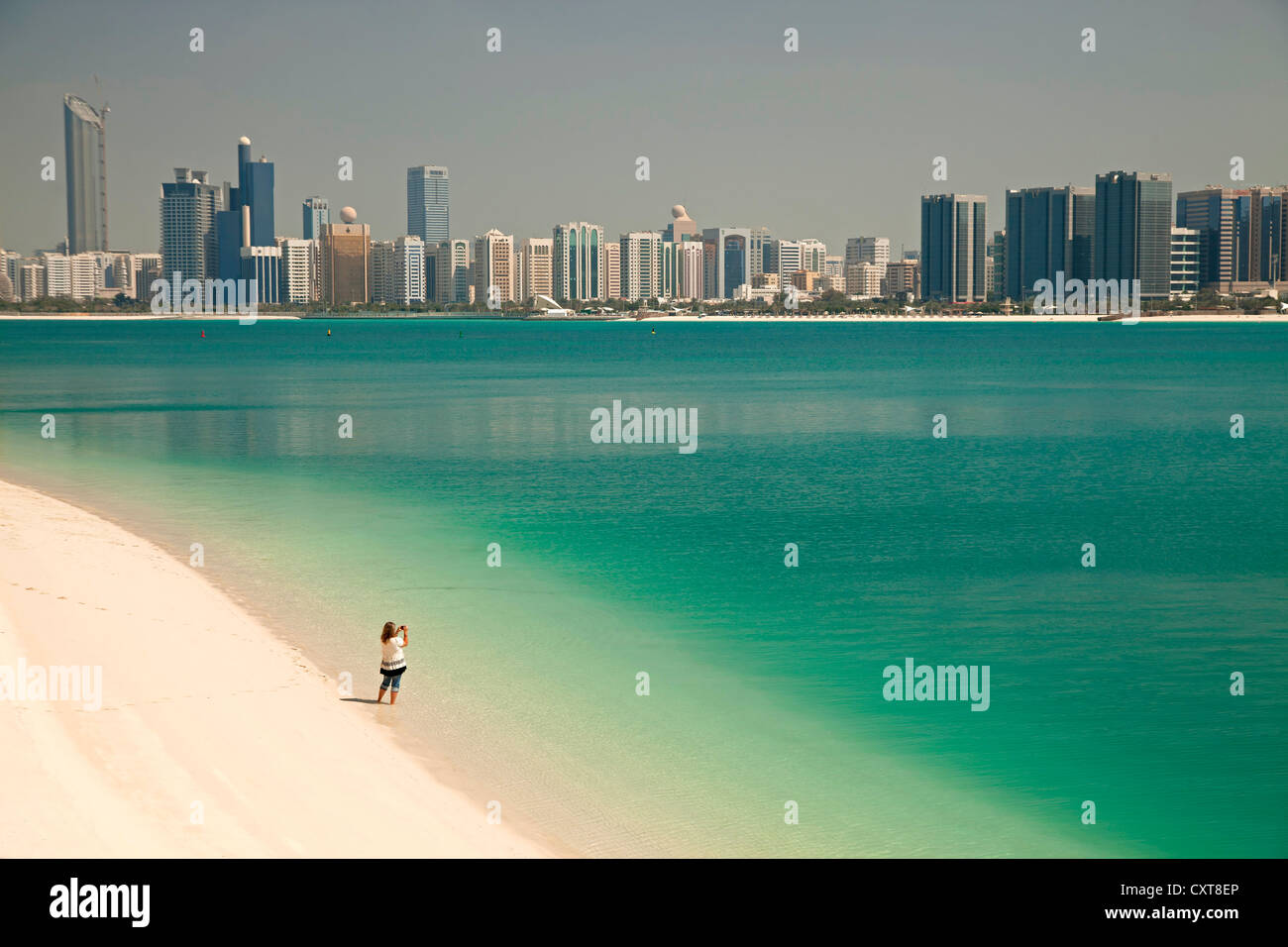 Einzelne Touristen am Strand vor dem Heritage Village, ein Foto von der Skyline von Abu Dhabi Stockfoto
