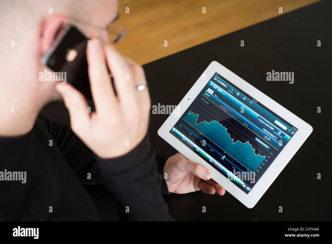 Mann, die Performance der FTSE Börsendaten auf iPad3 Tablettcomputer überprüfen Stockfoto