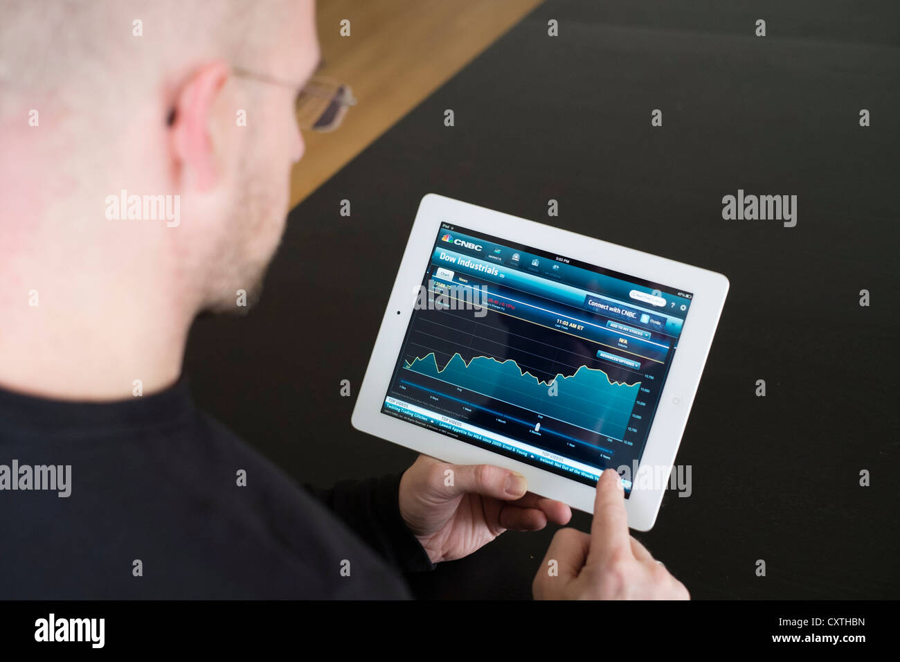Mann, die Performance des Dow Jones Aktienkurse auf iPad3 Tablettcomputer überprüfen Stockfoto