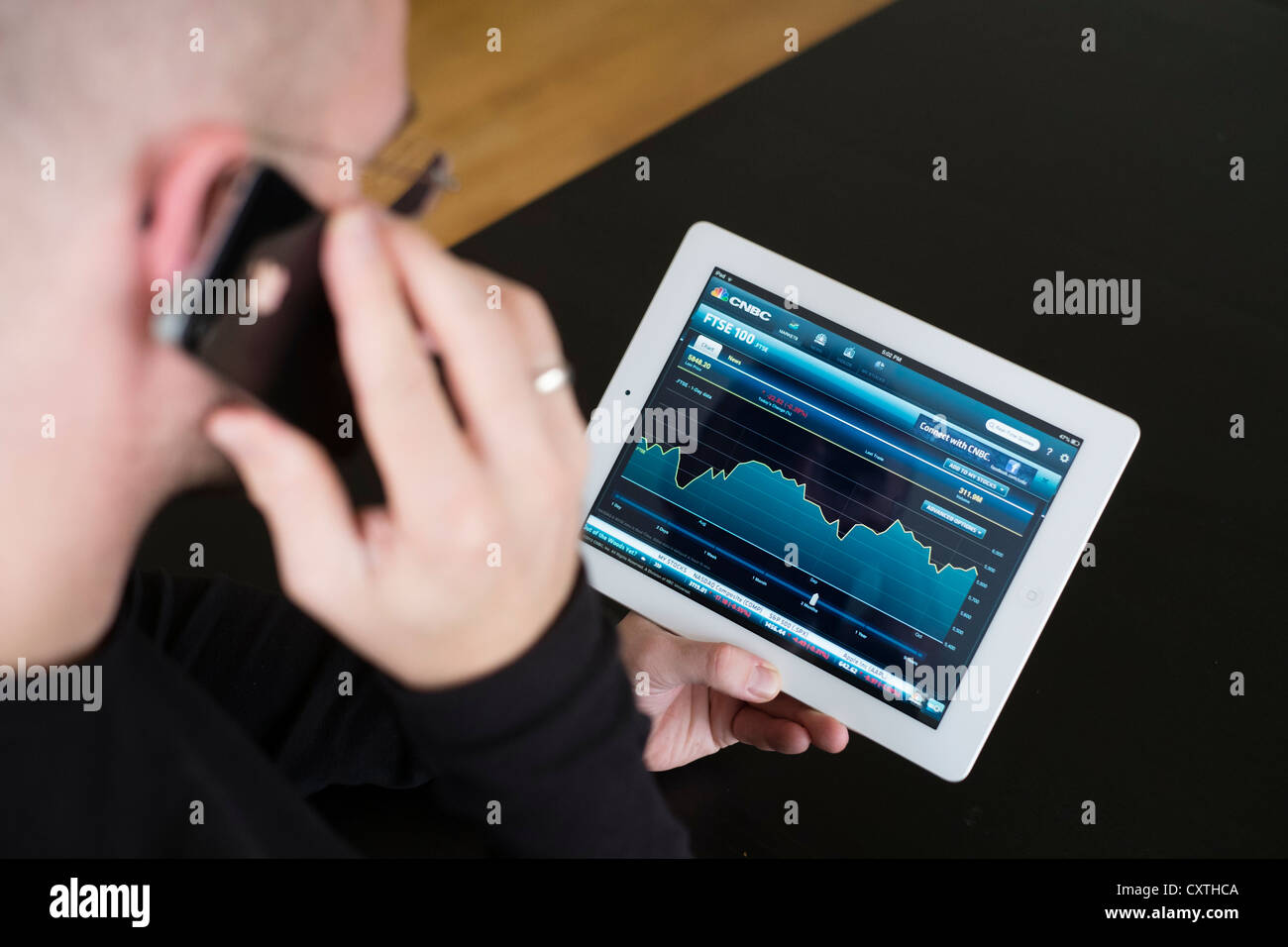 Mann, die Performance der FTSE Börsendaten auf iPad3 Tablettcomputer überprüfen Stockfoto