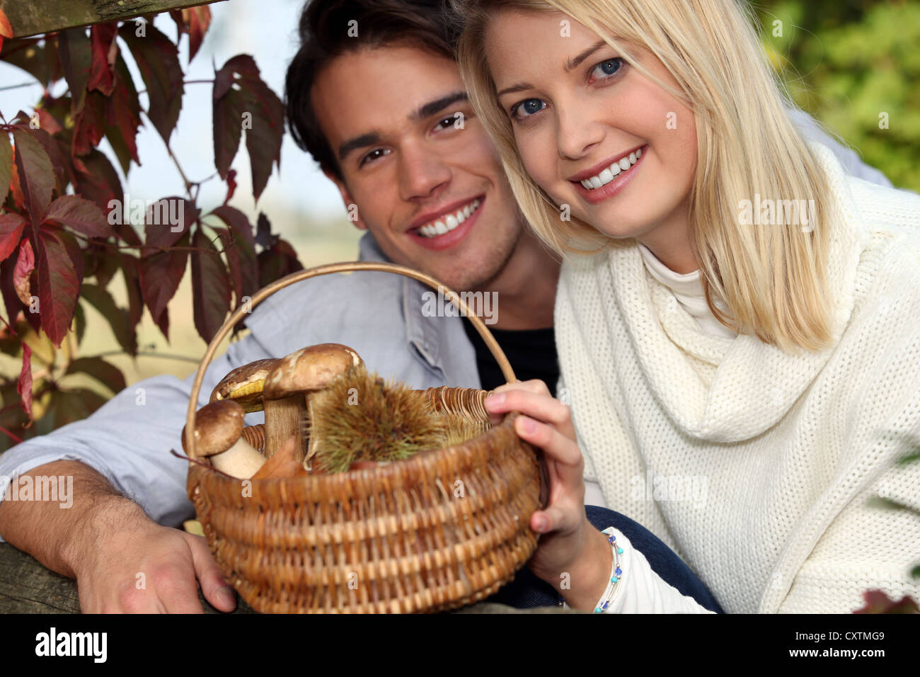 Paar sammeln Kastanien und Pilze im Wald Stockfoto