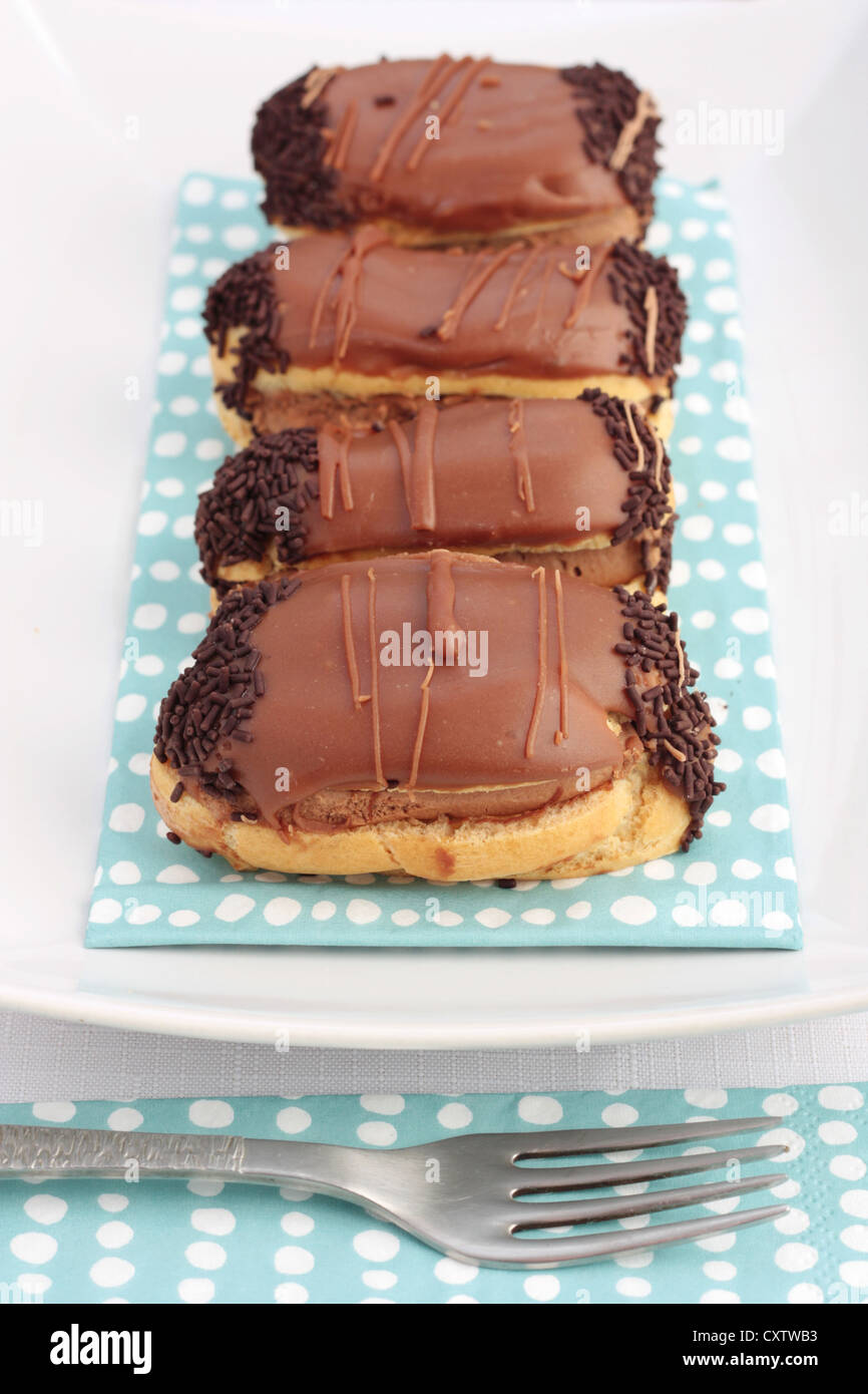 Ein Teller mit Schokolade Eclairs oder Choux Gebäck gefüllt mit Schokoladencreme und Schokoladenglasur bedeckt. Stockfoto