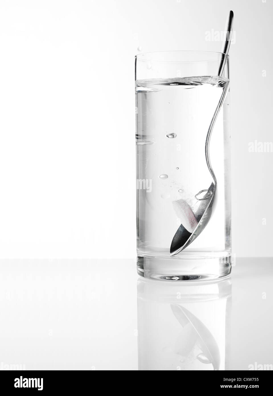 Pille auf einem Löffel in ein Glas Wasser auflösen Stockfoto
