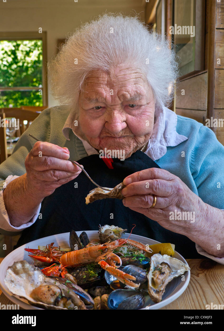 Glückliche ältere 99 Jahre alte Dame genießen einen Luxus Schale Fisch Essen im großen Speisesaal Anlage Stockfoto