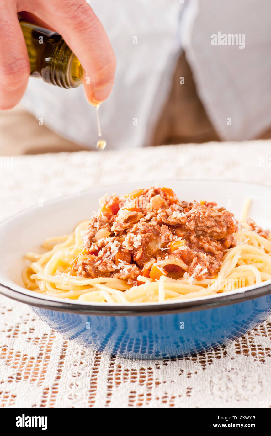 Portion Pasta alla Bolognese. Der Koch ist das Olivenöl oben hinzufügen. Stockfoto