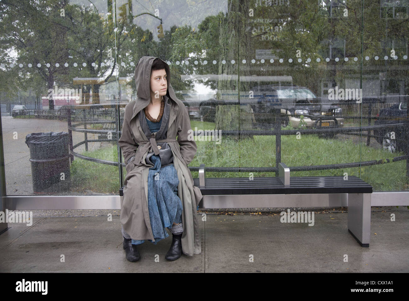 Junge Frau wartet auf einen Bus an einem regnerischen Tag von Prospect Park Parade Gelände in Brooklyn, New York. Stockfoto