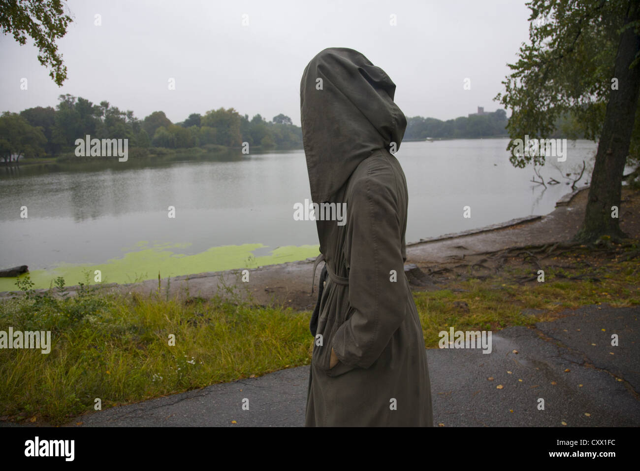Junge Frau allein an einem regnerischen Tag entlang des Sees im Prospect Park in Brooklyn, New York. Stockfoto