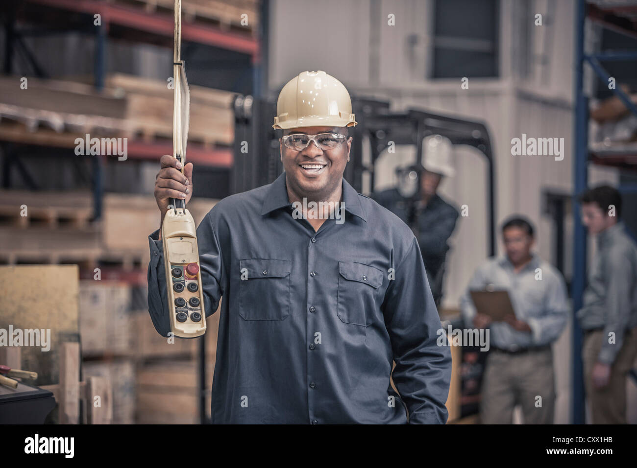 Afrikanische amerikanische Arbeiter halten Systemsteuerung in Fabrik Stockfoto