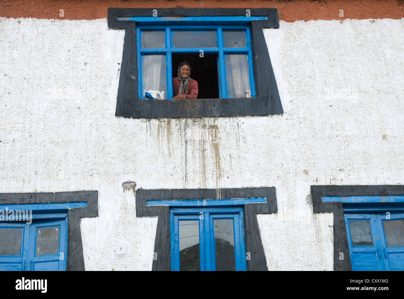 Eine Frau schaut aus ihrem Fenster im Dorf Kibber, Spiti, Nordindien Stockfoto