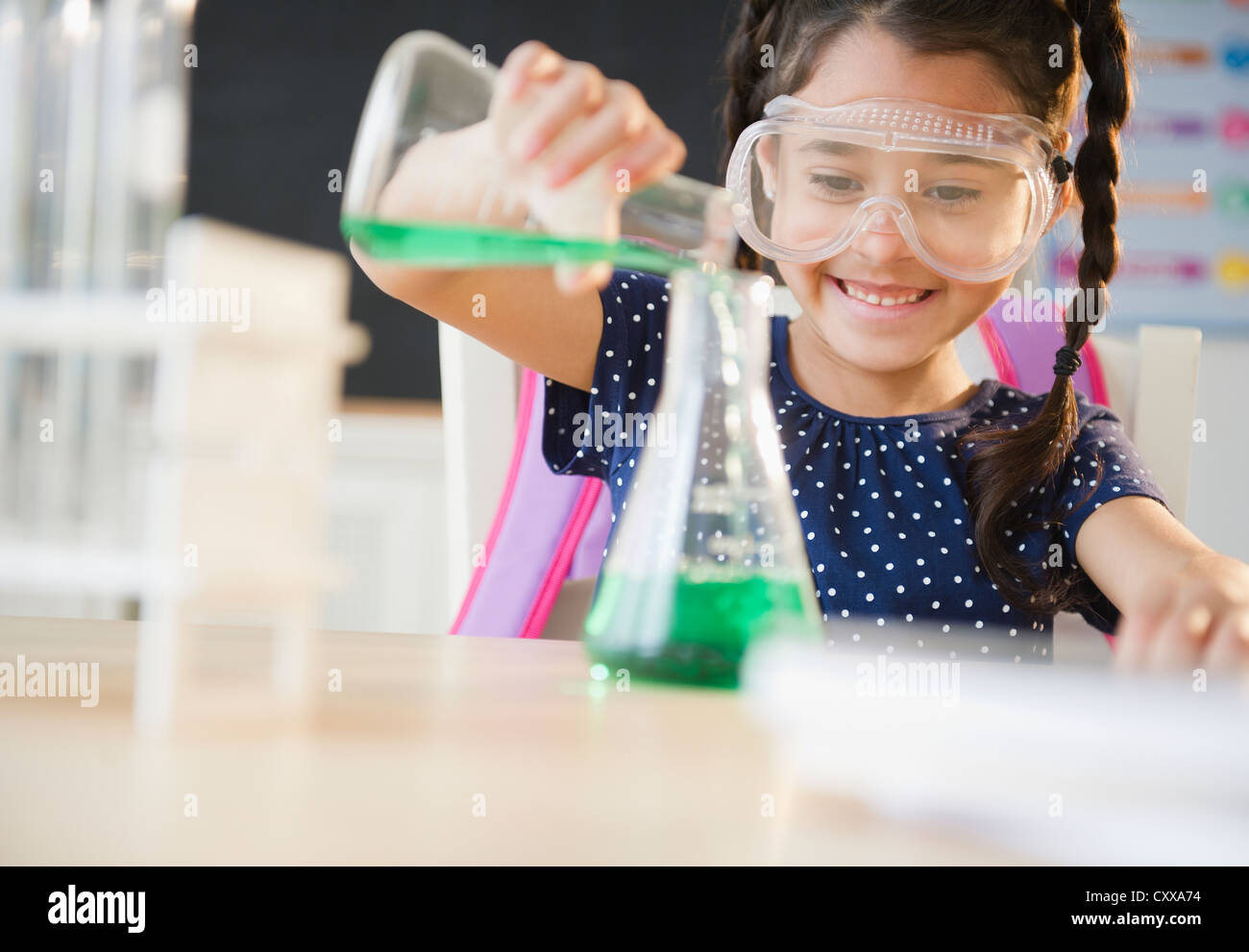 Gemischte Rassen Mädchen Gießen Flüssigkeit im Chemieunterricht Stockfoto