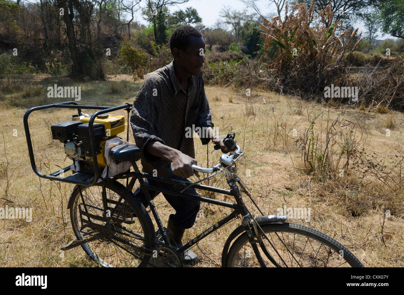Wirtschaftender Landwirt seine kleine Bewässerung Pumpe auf seinem Fahrrad zu transportieren. Monze Bereich. Sambia. Stockfoto