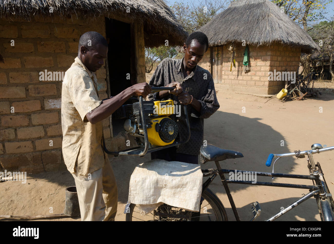 Wirtschaftender Landwirt seine kleine Bewässerung Pumpe auf seinem Fahrrad zu transportieren. Monze Bereich. Sambia. Stockfoto