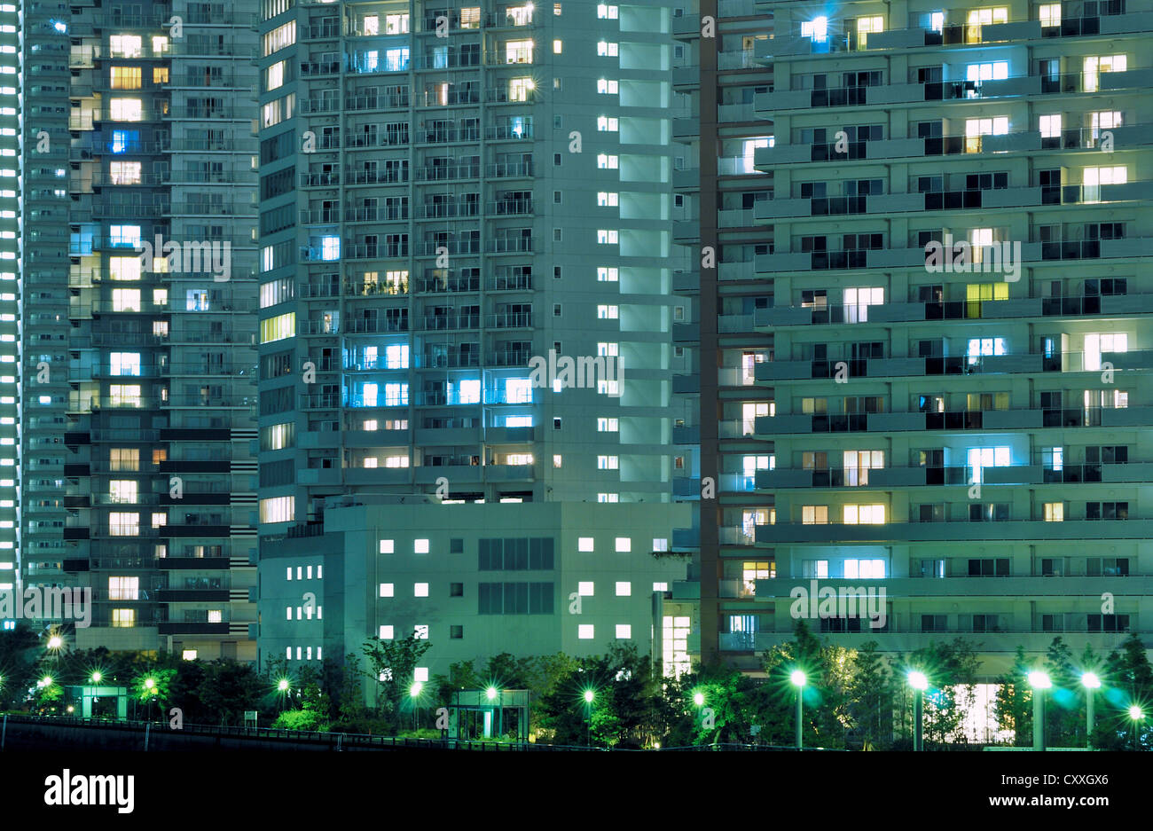 Nacht-Wohnhaus mit vielen Fenstern mit Straßenlaternen unten beleuchtet Stockfoto