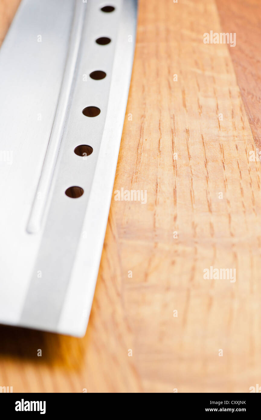 Messer mit Löchern auf Holzbrett liegend Stockfoto