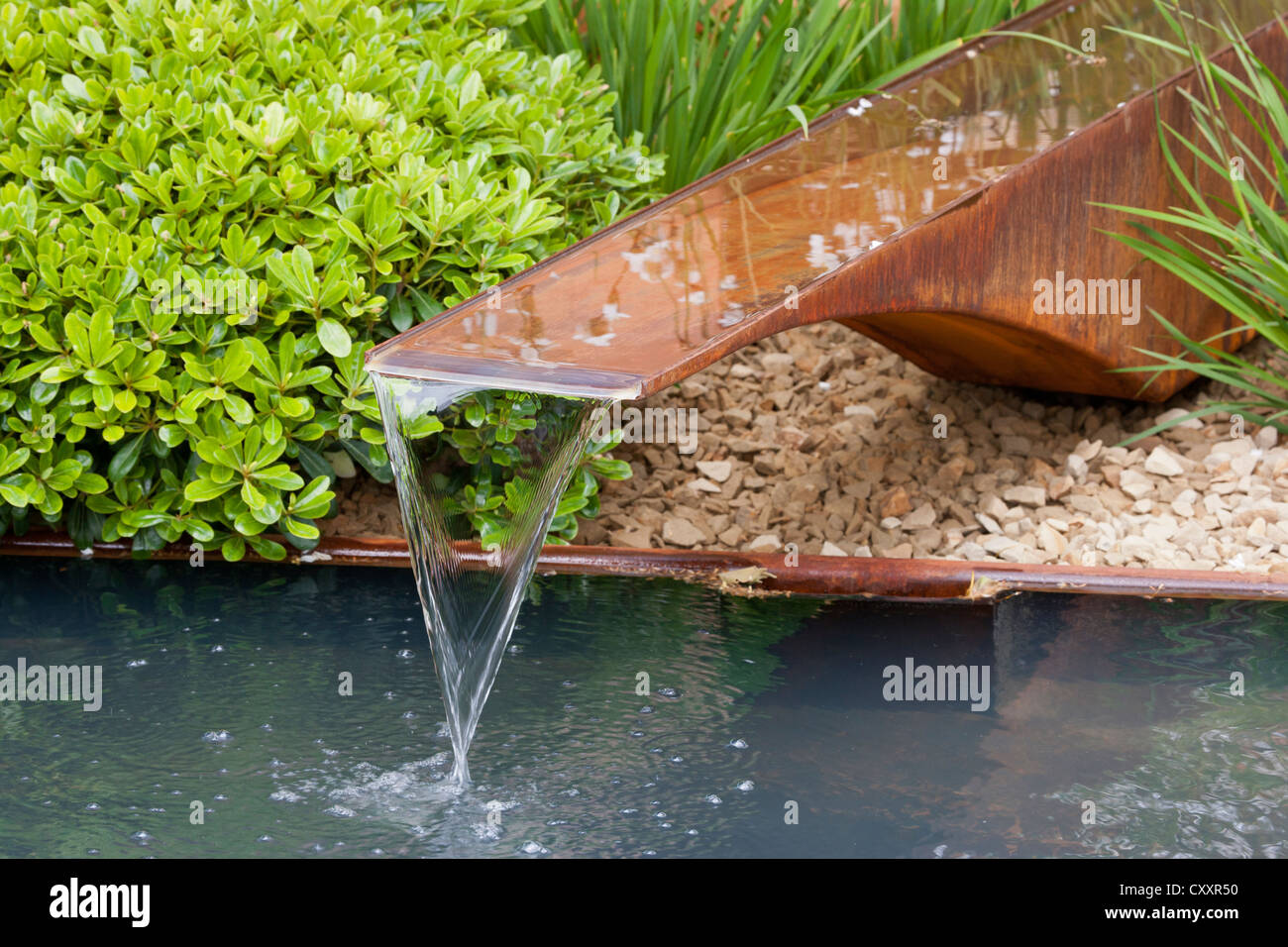 Ein Garten mit Gartenrillwasser aus Kupferwasser Randpflanzen, die einen kleinen Teich in Großbritannien Pflanzen Stockfoto