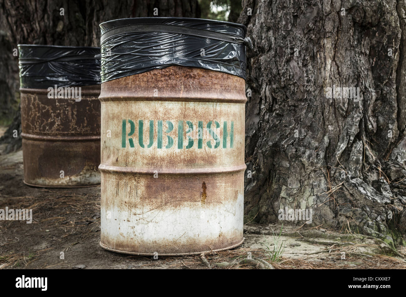 Rostige Blech Mülleimer mit Wort "Müll" neben einem knorrigen Baum, Neuseeland Stockfoto