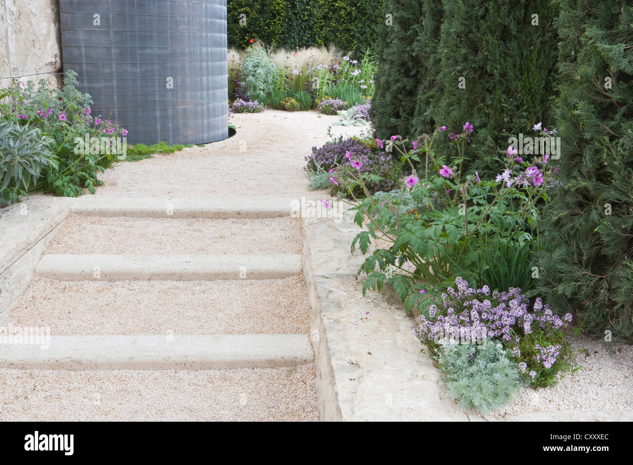 Moderner, moderner Schottergarten mit Steintreppen und Blumenkränzen und Ziergräsern, Chelsea RHS, Blumenshow-Gärten, London, Großbritannien Stockfoto