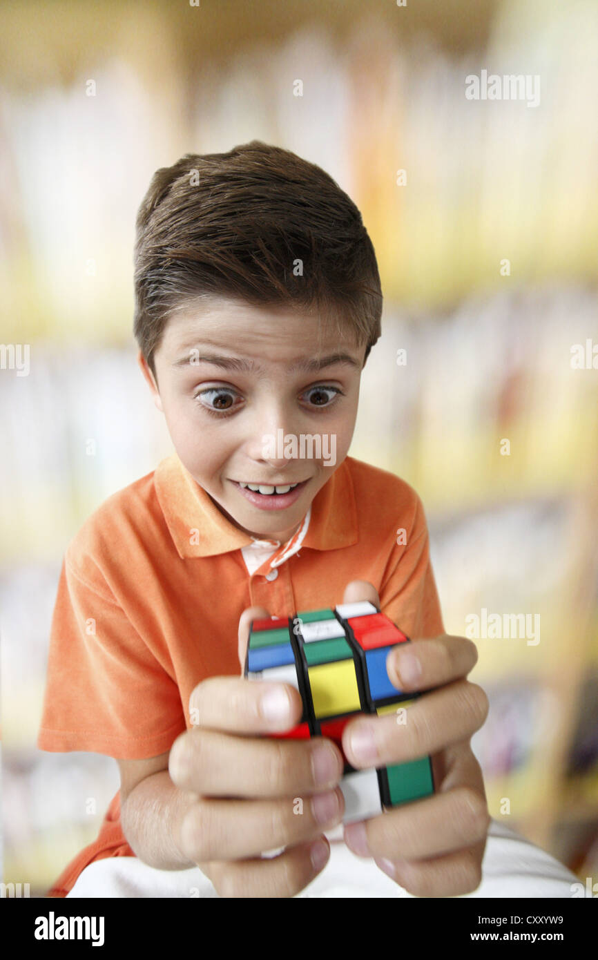 Überrascht aussehende junge mit einem magischen Würfel Stockfoto