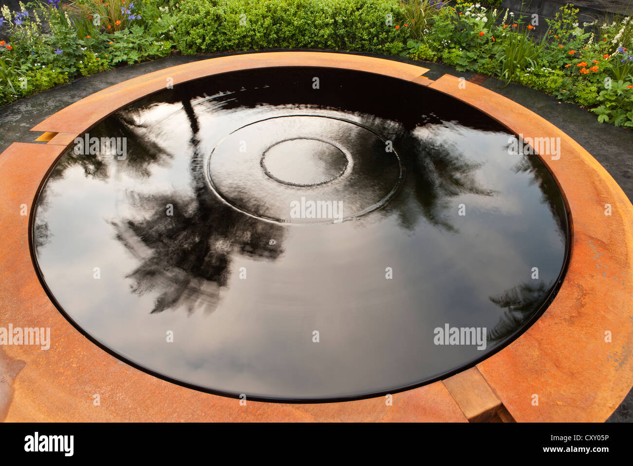 In einem kleinen Stadtgarten im Vereinigten Königreich, Chelsea RHS Flower Show Gardens London, befindet sich ein Teich aus Corten-Stahl, dessen Wasser im Pool liegt Stockfoto
