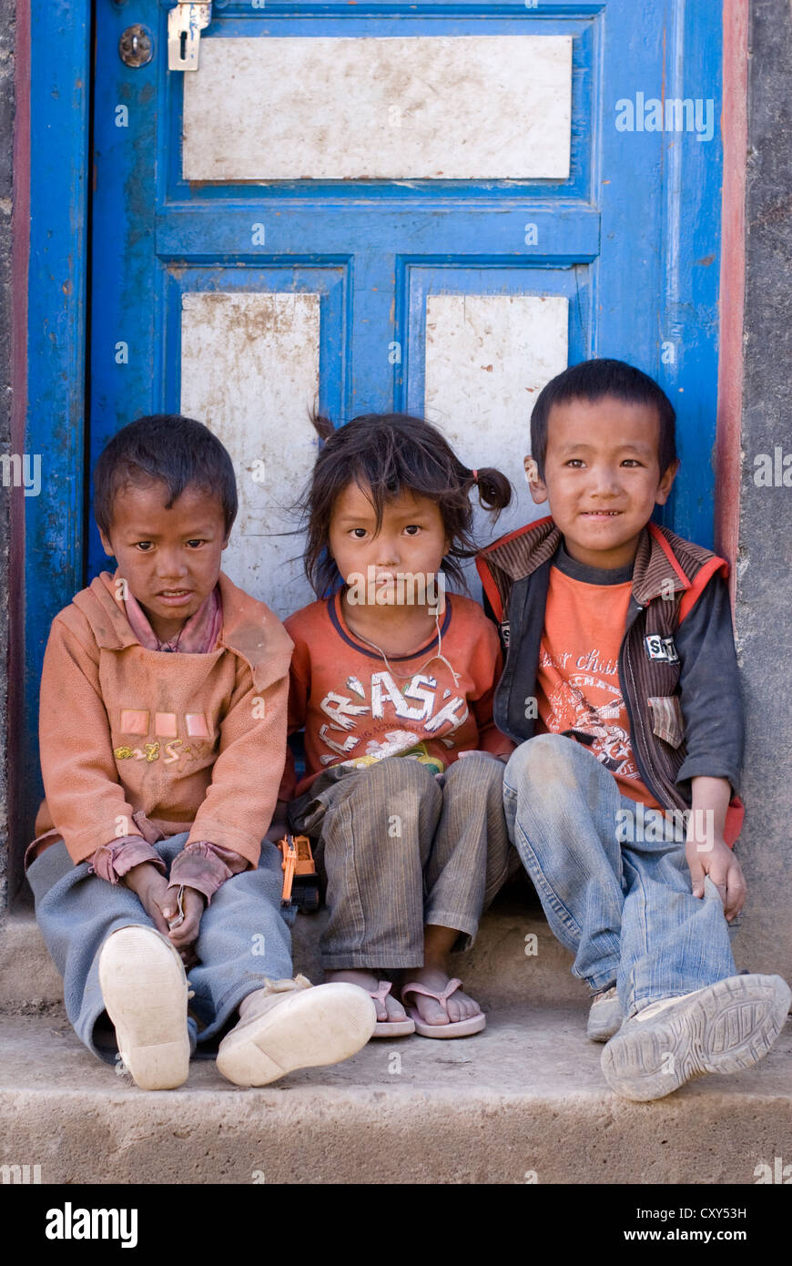 Drei Freunde sitzen in der Tür eines Hauses in Schlamm Dorf, Spiti, Nordindien Stockfoto