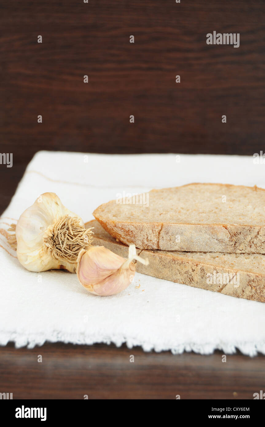 Scheiben Brot und Knoblauch auf dem weißen Tuch Stockfoto