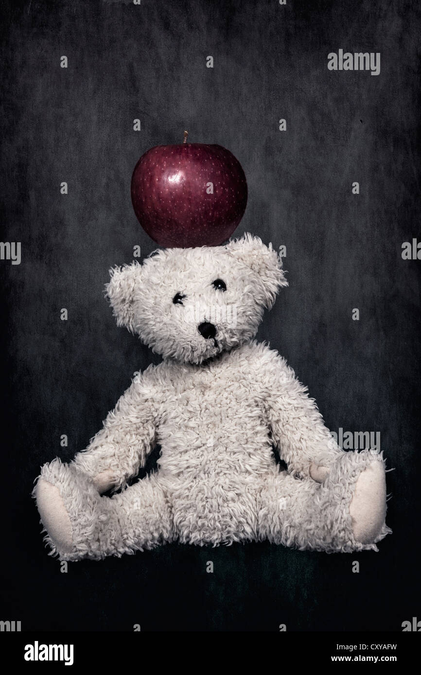 ein Weißer Teddybär mit ein roter Apfel auf dem Kopf Stockfoto