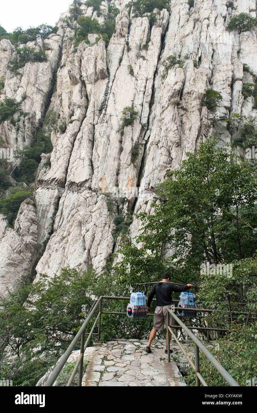 Ein Mann Ausgleich schwere Pakete auf dem Weg zum San Huang Zhai Kloster auf dem Song-Berg, China Stockfoto