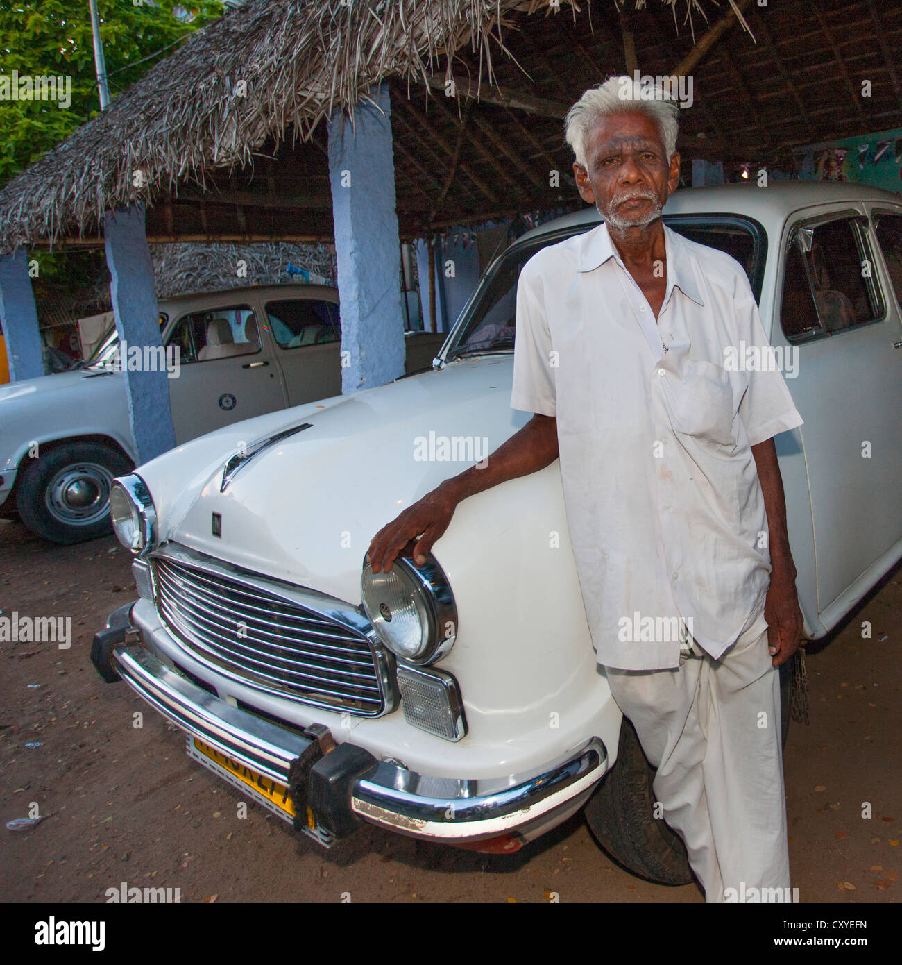 Alter Mann mit grauem Haar posiert stolz vor einem berühmten indischen Auto namens den Botschafter, Trichy, Indien Stockfoto