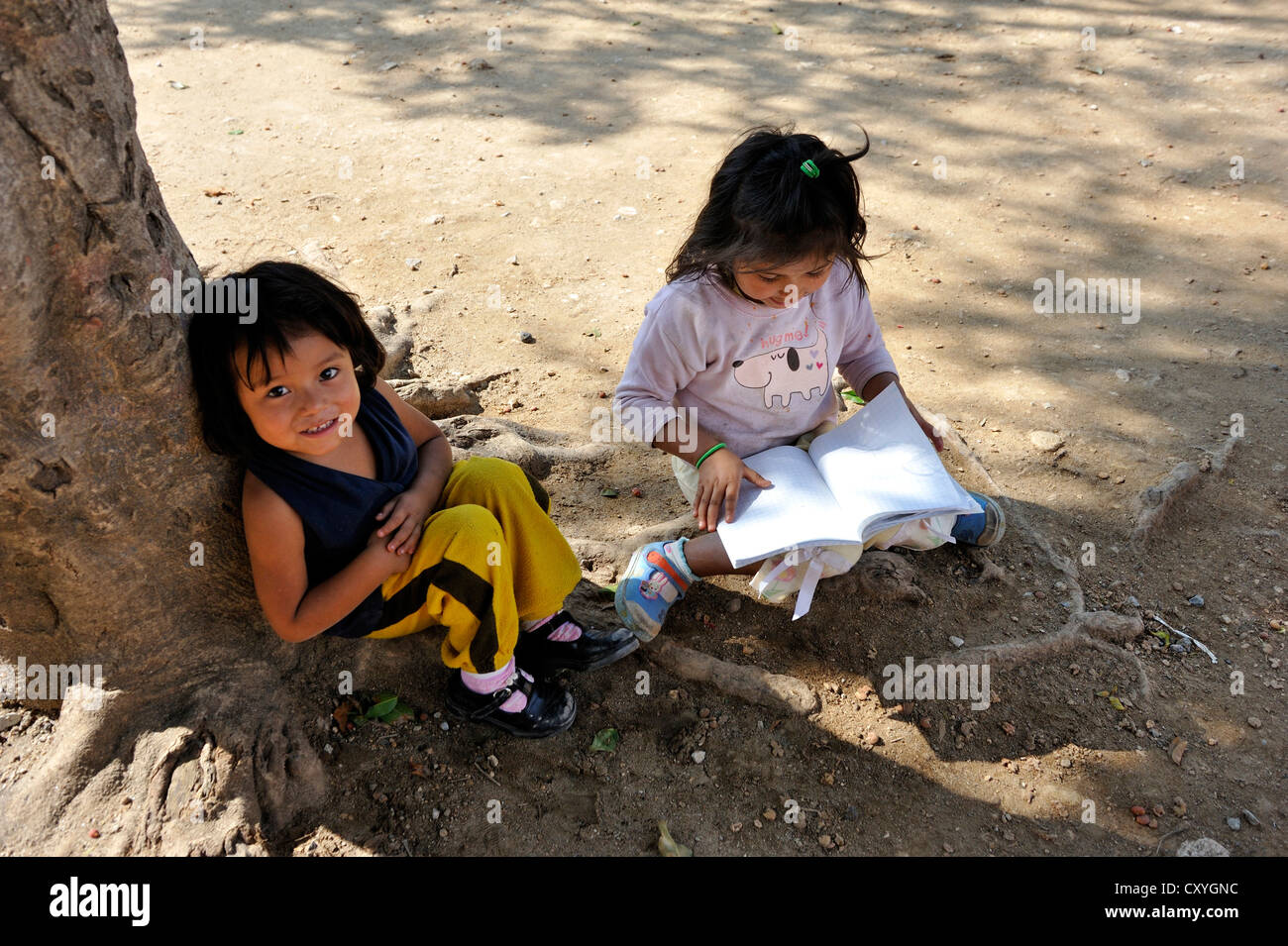 Zwei Mädchen mit Hefte sitzen im Schatten eines Baumes, Lomas de Santa Faz Slum, Guatemala-Stadt, Guatemala Stockfoto