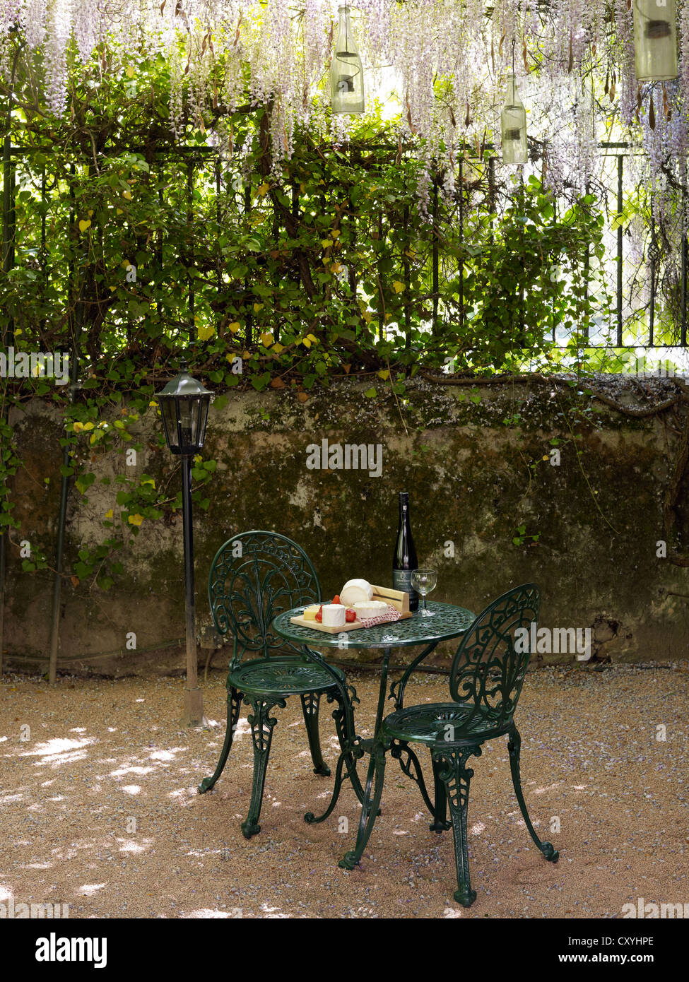 Stilleben, Käsebuffet auf eine Runde, antike gusseiserne Gartentisch mit zwei Stühlen in einem romantischen Innenhof Stockfoto